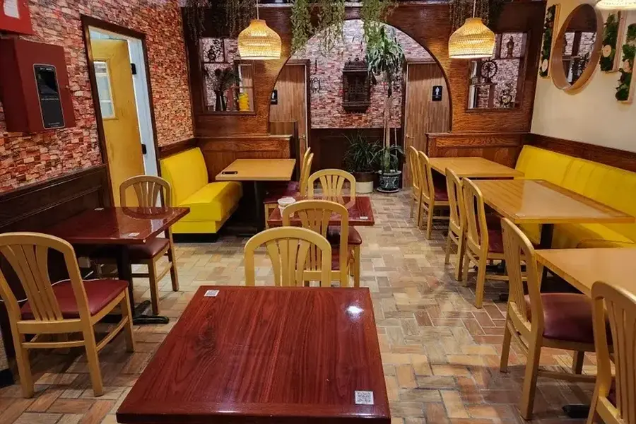 an interior shot of a restaurant with small tables and yellow chairs