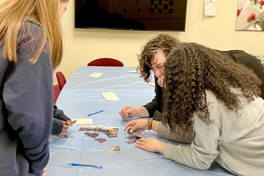 three people leaning over a table piecing paper together
