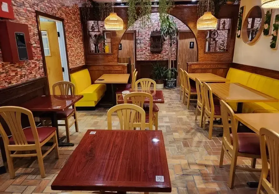 an interior shot of a restaurant with small tables and yellow chairs