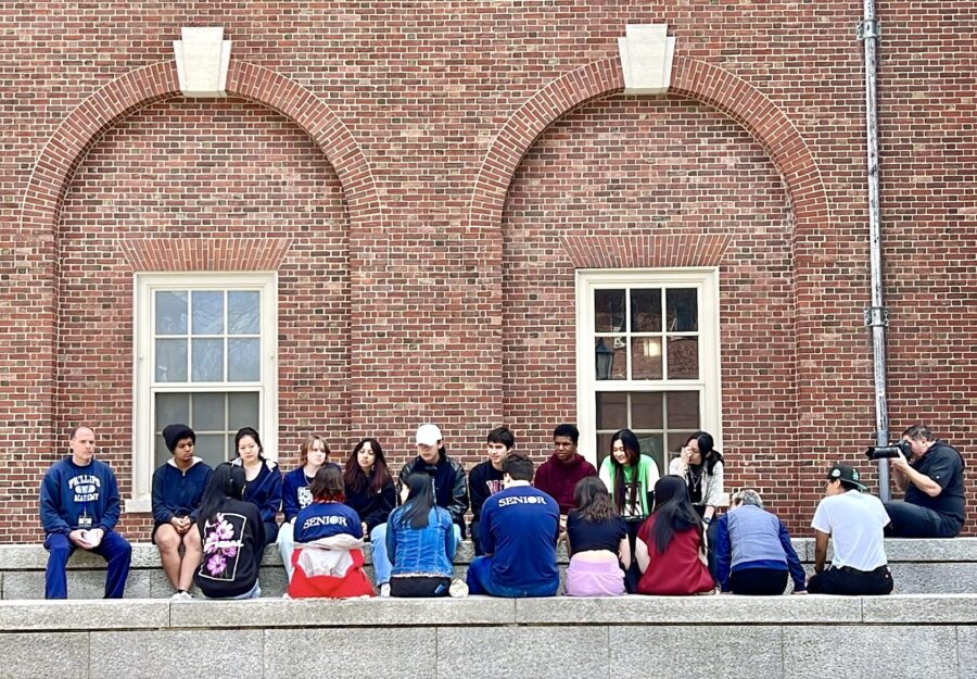 workshop students sitting on stoop by brick wall