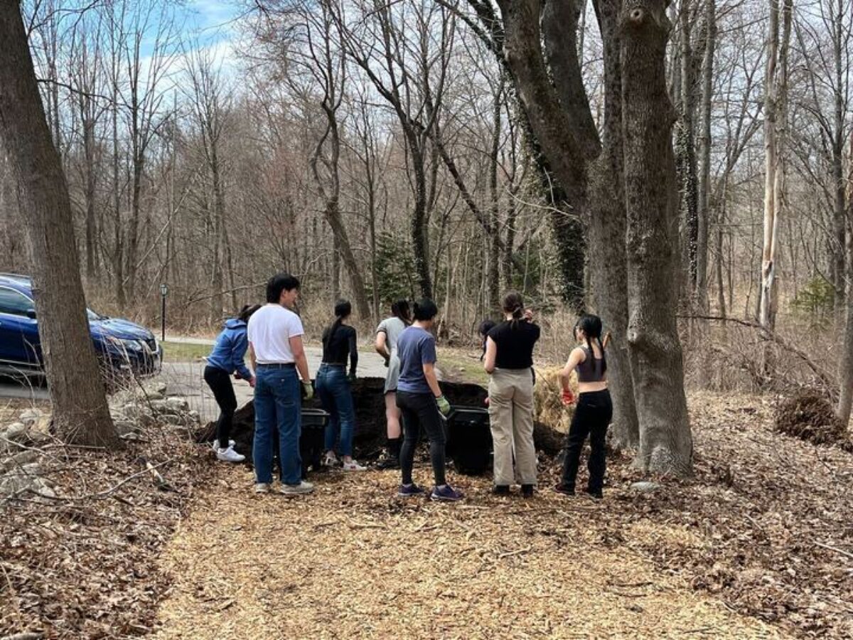 group of teens outside standing in front of a giant mound of earth