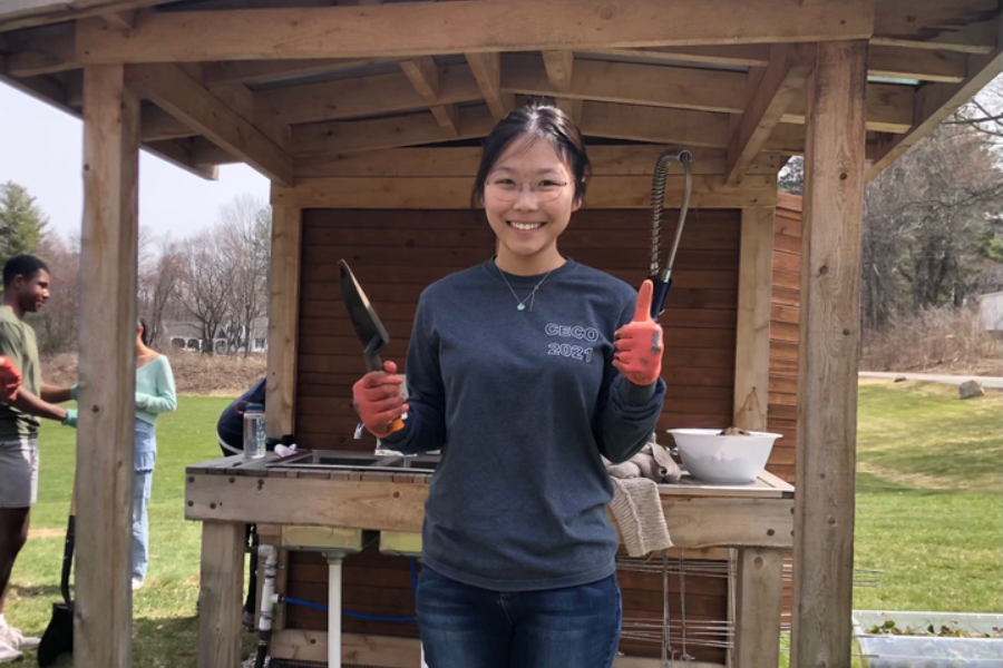 the author standing outside near garden holding gardening tools