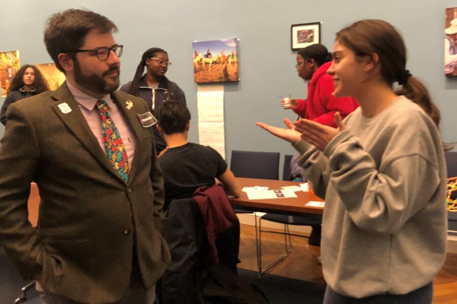 bearded man standing talking to a younger female student