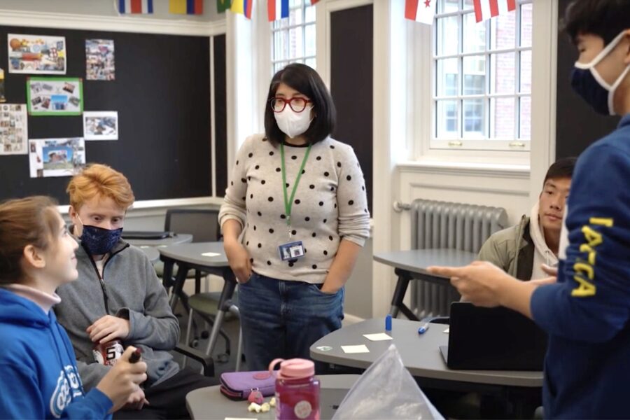 female teacher standing in a classroom surrounded by four students