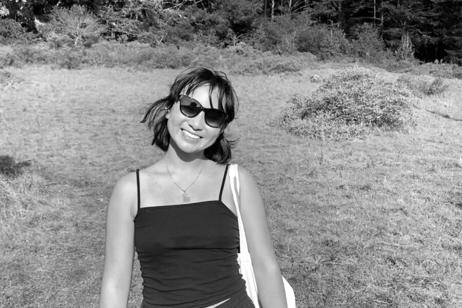 Katherine Wang ’21 stands in a field in summertime with a phone in her hand