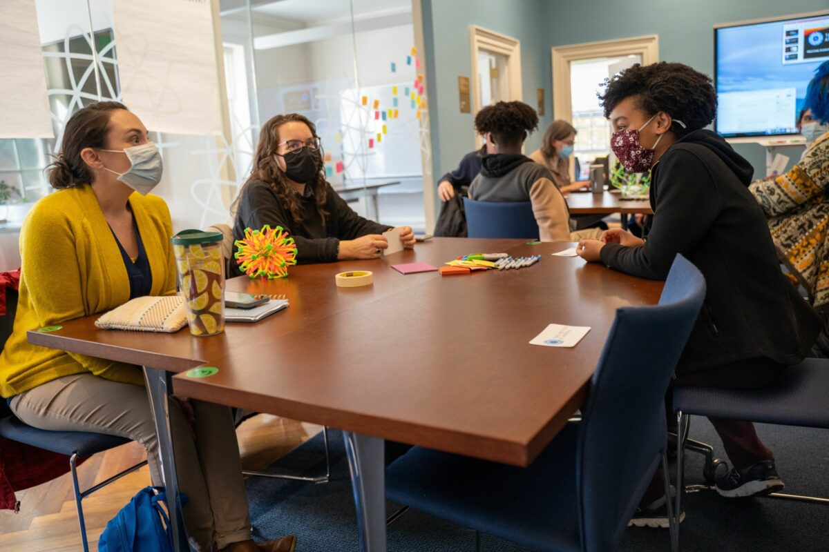 2 faculty members and 1 student sit at a table discussing Tang Institute projects